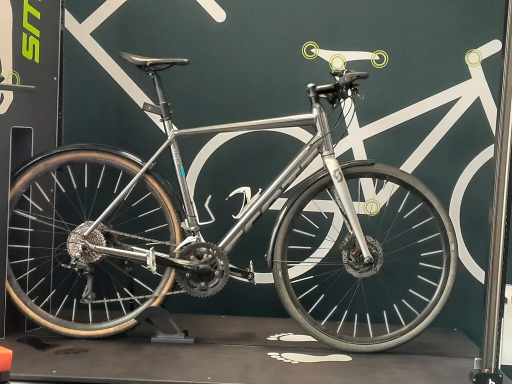 Graues Rennrad auf der Fitting-Plattform vor der SmartFit-Wand