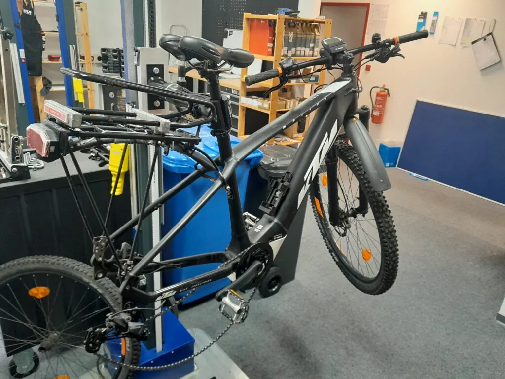 Schwarzes E-Mountainbike im Montageständer der Werkstatt