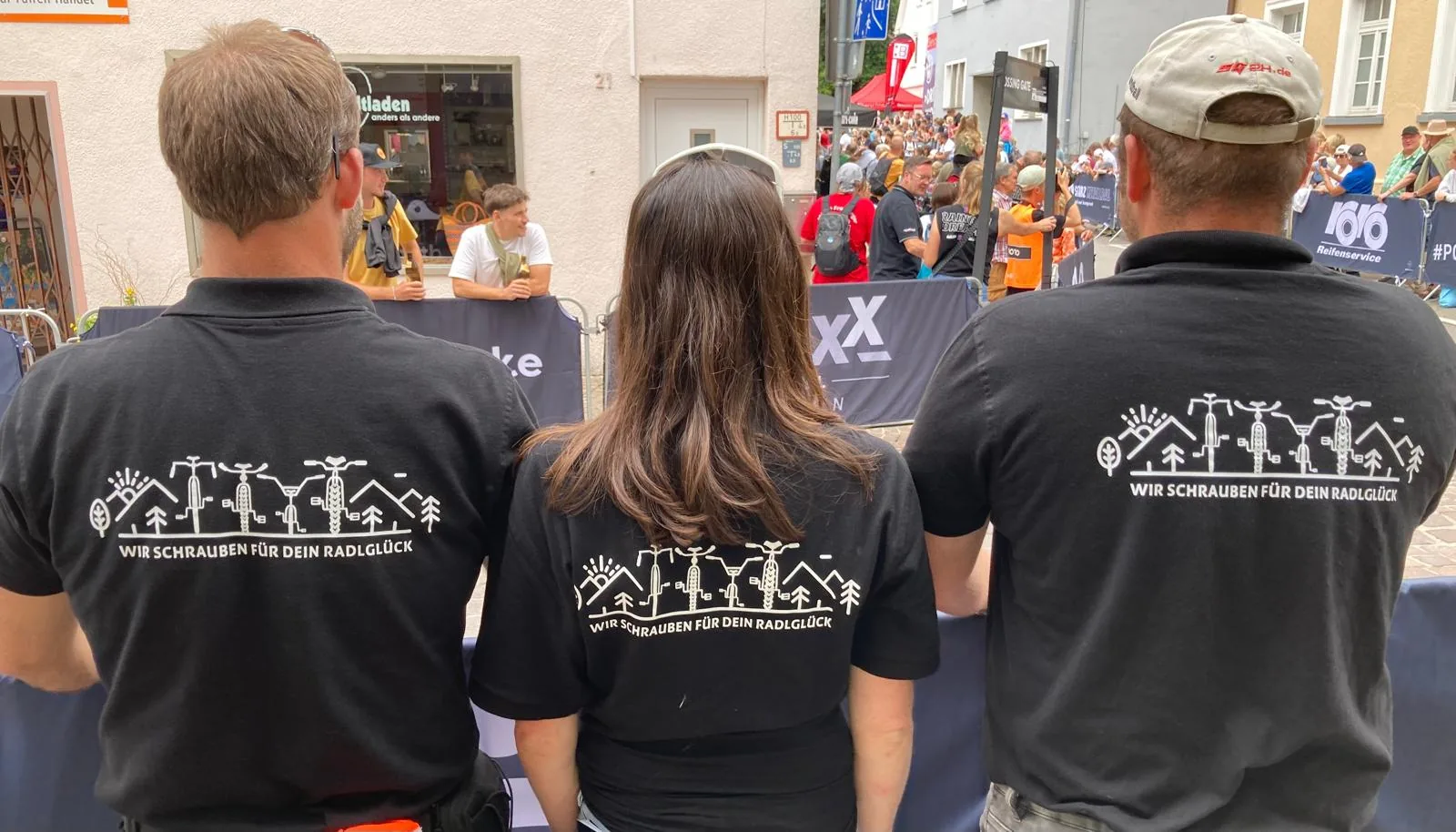 Drei Personen in Radlwelt-Shirts mit dem Aufdruck „Wir schrauben für dein Radlglück“